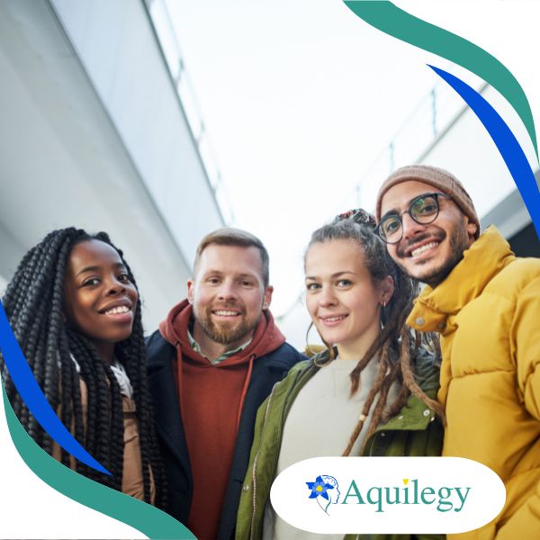 Four people smiling at the camera outdoors near a modern building, with "Aquilegy" logo in the bottom right corner.